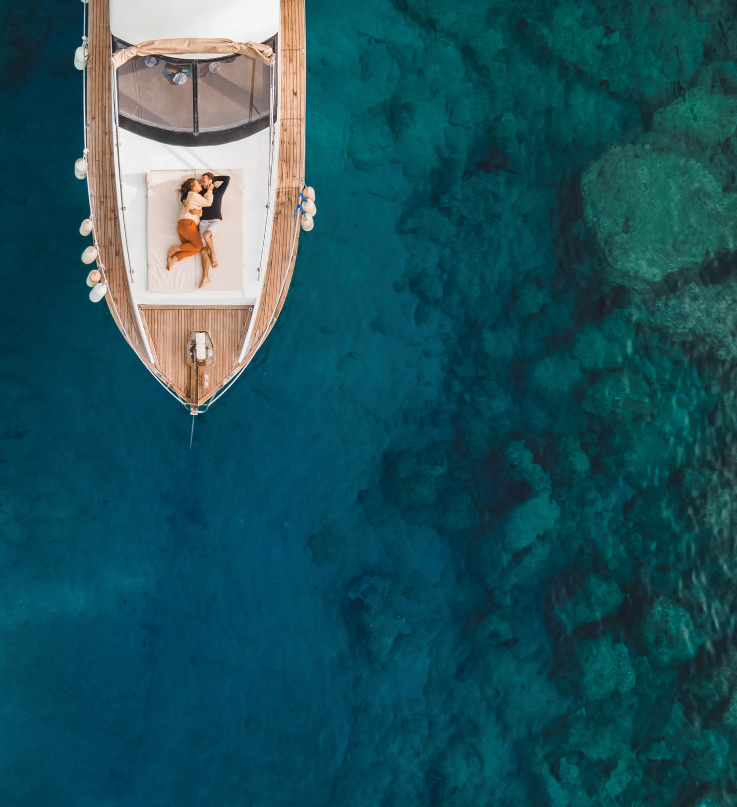 Luxury honeymoon cruise. Vacations of wealth people. Young successful couple travel and adventure on private boat. Dreamy and idyllic seascape from above. Wanderlust journey
